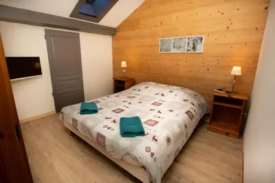 a bedroom with a bed and a wooden wall at La Ferme du Lay in Arâches-la-Frasse