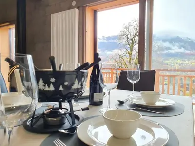 a table with plates and wine glasses and a window at Samoens - luxury 4 bedroom top floor apartment with spectacular views in Samoëns