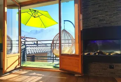 a window with a yellow umbrella on a balcony at Le Chamois d'Assy, résidence alpine de charme in Passy