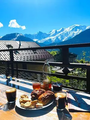 a plate of pastries and drinks on a table with mountains at Le Chamois d'Assy, résidence alpine de charme in Passy