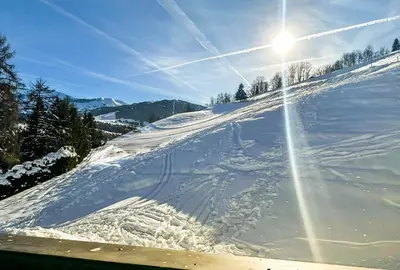 a snow covered slope with the sun shining on it at Chalet Orchidee Megeve sur les pistes in Megève