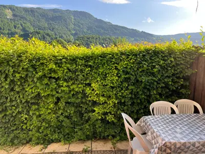 a table and chairs in front of a hedge at Samoens centre - appartement une chambre in Samoëns