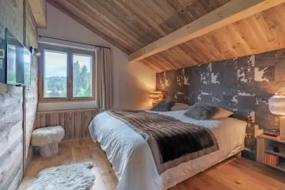 a bedroom with a large bed and a window at Très bel appartement Duplex 9 couchages in Megève