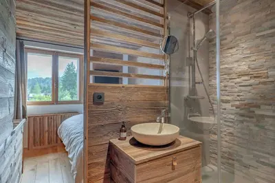 a bathroom with a sink and a shower and a bed at Très bel appartement Duplex 9 couchages in Megève