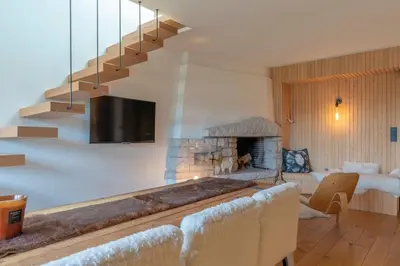 a living room with a staircase and a fireplace at Très bel appartement Duplex 9 couchages in Megève