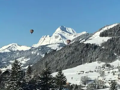two hot air balloons flying over a snow covered mountain at Très bel appartement Duplex 9 couchages in Megève
