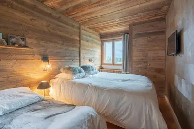 two beds in a room with wooden walls at Très bel appartement Duplex 9 couchages in Megève
