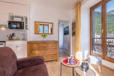 a kitchen and dining room with a wooden table with plates on it at Charming flat right in the city centre in Chamonix-Mont-Blanc
