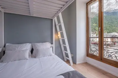 a bedroom with a bed with a ladder and a window at Charming flat right in the city centre in Chamonix-Mont-Blanc