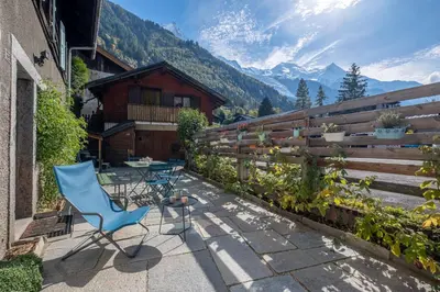 a patio with chairs and a table and a fence at SmartStay Loft - Exterieur et vue Mont Blanc in Chamonix-Mont-Blanc