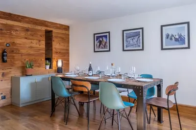 a dining room with a table with chairs and wine glasses at SmartStay Loft - Exterieur et vue Mont Blanc in Chamonix-Mont-Blanc
