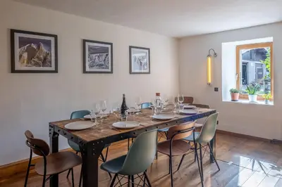 a dining room table with chairs and a bottle of wine at SmartStay Loft - Exterieur et vue Mont Blanc in Chamonix-Mont-Blanc