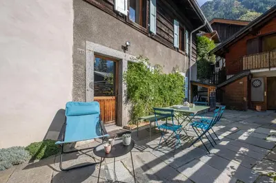 a patio with chairs and a table in front of a building at SmartStay Loft - Exterieur et vue Mont Blanc in Chamonix-Mont-Blanc