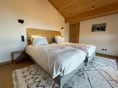 a bedroom with a large bed with a wooden headboard at Chalet Petit Val in Combloux