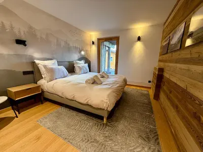 a bedroom with a bed in a room with a wall at Chalet Petit Val in Combloux
