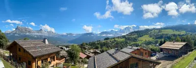 a group of houses on a hill with mountains in the background at Chalet Petit Val in Combloux