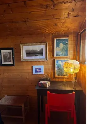 a room with a wooden wall with a table and a red chair at Hameau de la Côte in Les Houches