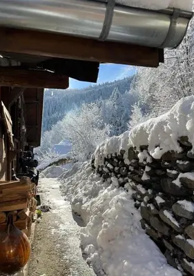 a stone wall covered in snow next to a building at Hameau de la Côte in Les Houches