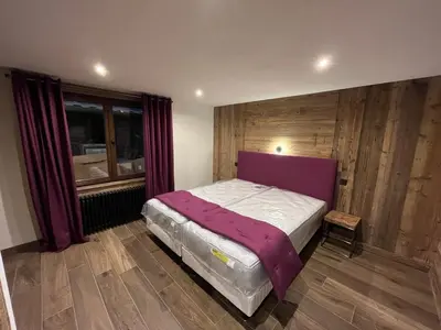 a bedroom with a bed with a purple head board at La Belle Etoile in Saint-Gervais-les-Bains