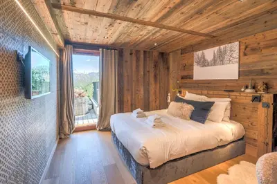 a bedroom with a bed in a room with wooden walls at Appartement Horizon Panoramique - Welkeys in Combloux