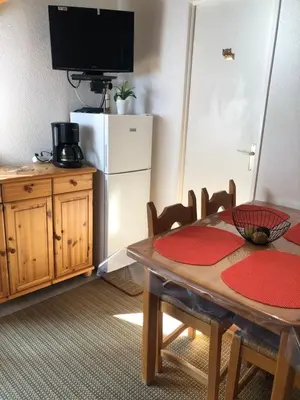 a dining room with a table and a refrigerator at Appartement Balcon piscine tennis vue Montagne in Saint-Gervais-les-Bains