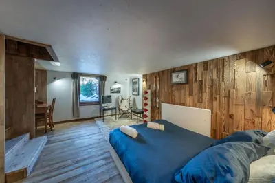 a bedroom with a blue bed and wooden walls at Le Chalet 138 Megève séjour pour 8 confort espace charme calme in Demi-Quartier