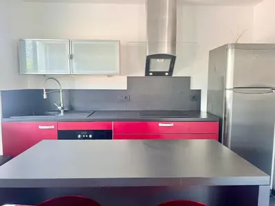 a kitchen with red cabinets and a stainless steel refrigerator at Charmant appartements Sallanches in Sallanches