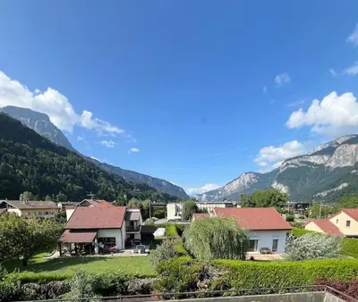 a village with houses and mountains in the background at Charmant appartements Sallanches in Sallanches