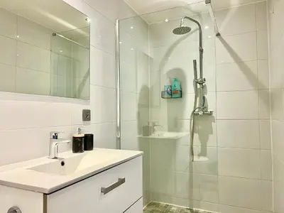 a white bathroom with a shower and a sink at Charmant appartements Sallanches in Sallanches