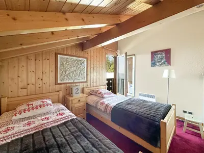 two beds in a room with wooden walls at CH143 - Chalet cosy 6 personnes in Les Carroz d'Araches