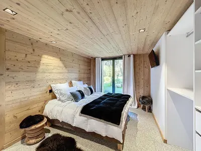 a bed in a room with a wooden wall at Chalet de luxe avec vue Mont Blanc et parking - FR-1-560-150 in Sallanches