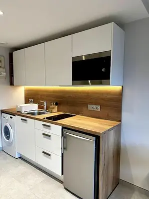 a kitchen with white cabinets and a sink and a dishwasher at Joli petit studio neuf in Saint-Gervais-les-Bains
