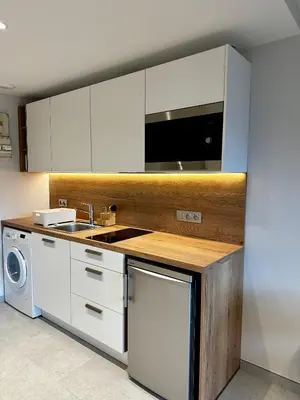 a kitchen with white cabinets and a sink and a dishwasher at Joli petit studio neuf in Saint-Gervais-les-Bains
