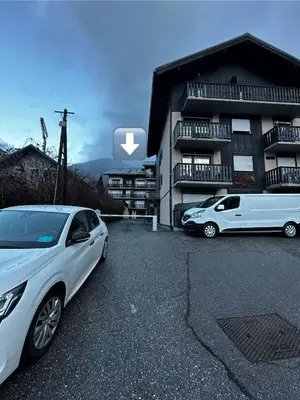 two cars parked in a parking lot in front of a building at Joli petit studio neuf in Saint-Gervais-les-Bains