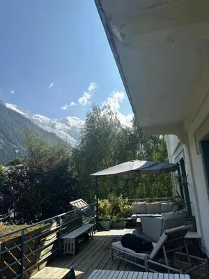 a deck with chairs and an umbrella on a house at 70sqm in heart of chamonix in Chamonix-Mont-Blanc