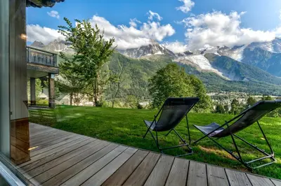 two chairs on a deck with mountains in the background at Chalet Hibou in Chamonix-Mont-Blanc