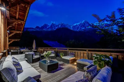 a deck with couches and a view of mountains at Chalet Hibou in Chamonix-Mont-Blanc