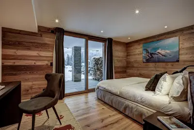 a bedroom with a bed and a desk and a window at Chalet Freya in Chamonix-Mont-Blanc