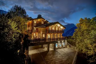 a house on a bridge in the woods at night at Chalet Kuma in Les Houches