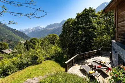 a group of benches sitting on a porch with mountains at Chalet Kuma in Les Houches