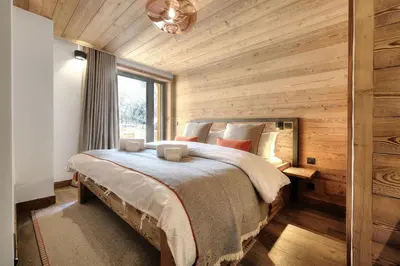a bedroom with a large bed in a room with wooden walls at Chalet Kuma in Les Houches