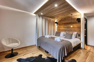 a bedroom with a large bed and a chair at Le Marti in Chamonix-Mont-Blanc