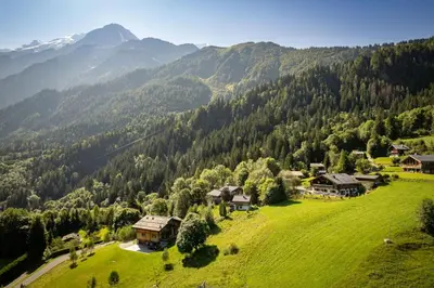 an aerial view of a green field with houses and mountains at Chalet Norel in Les Houches