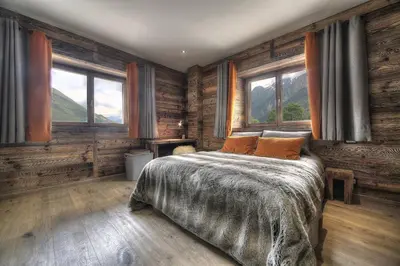 a bedroom with a bed with wooden walls and windows at Chalet Norel in Les Houches