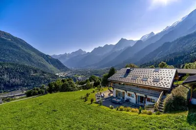 a house on a hill with mountains in the background at Chalet Norel in Les Houches