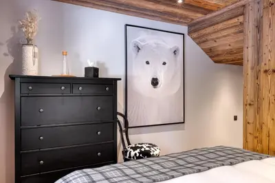 a bedroom with a black dresser and a picture of a polar bear at Appartement Élégance Mont Blanc - Welkeys in Combloux