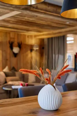 a white vase with orange flowers sitting on a table at Appartement Élégance Mont Blanc - Welkeys in Combloux