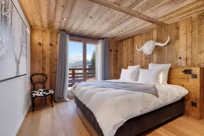 a bedroom with a bed with a wooden wall at Appartement Élégance Mont Blanc - Welkeys in Combloux