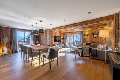 a dining room and living room with a table and chairs at Appartement Élégance Mont Blanc - Welkeys in Combloux