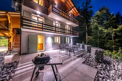 a house with a patio with tables and chairs at Le Bord Du Nant in Arâches-la-Frasse